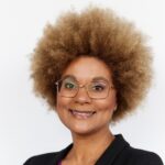 Portrait of woman with an afro wearing a black jacket and maroon blouse